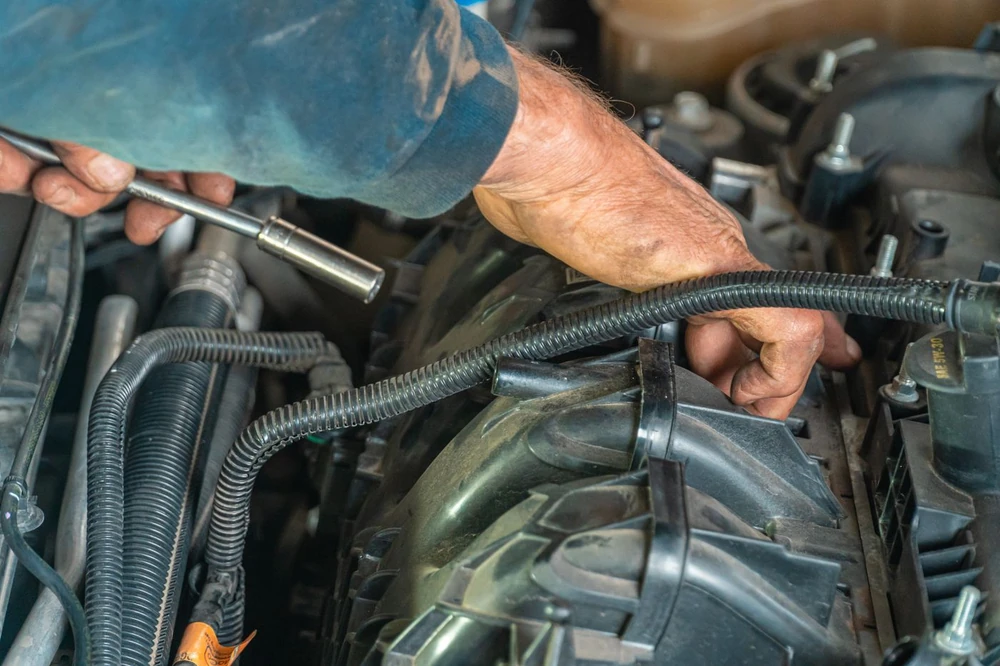 Manos trabajando con herramienta en el motor